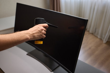 Someone is using a spray bottle to clean a television screen