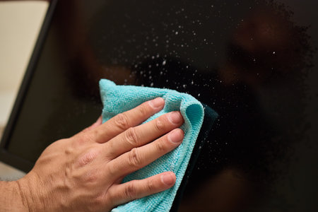 A person is using a cloth to clean a flat screen TV