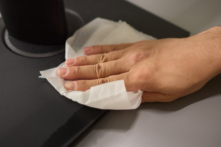A person is using a cloth to clean a flat screen TV