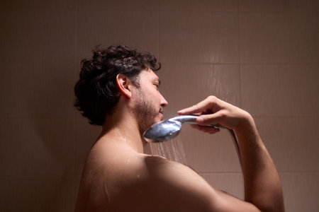 A man is taking a shower, enjoying the clean water to ensure good hygiene and relaxationの写真素材