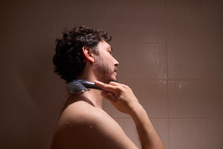 A man is taking a shower, enjoying the clean water to ensure good hygiene and relaxationの写真素材