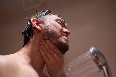A man is taking a shower, enjoying the clean water to ensure good hygiene and relaxationの写真素材