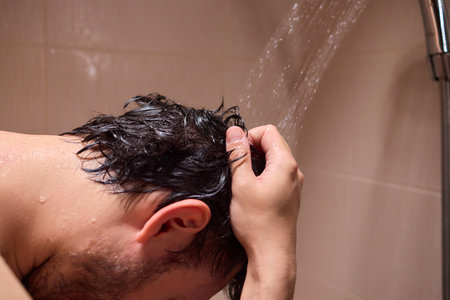 A man is taking a shower, enjoying the clean water to ensure good hygiene and relaxationの写真素材