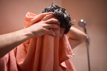 Drying hair with a towel after showering is important for hygiene and selfcare in a shower routineの写真素材