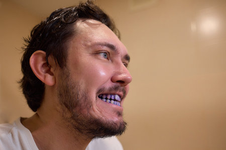 A man with blue teeth looks amused in a closeup shot, with a spontaneous and vibrant expression...