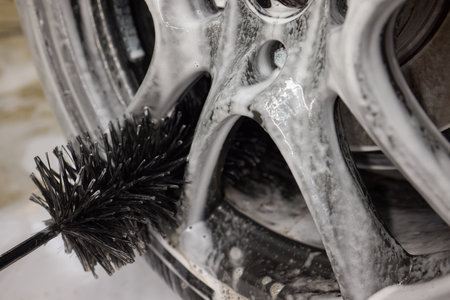 Cleaning car wheel thoroughly with brush and soap for maintenance and shiny resultの写真素材