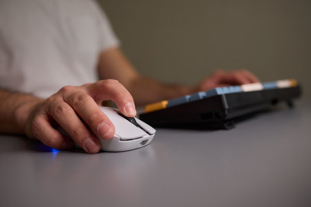 Person typing on keyboard and using a mouse at desk, focused on work technologyの写真素材