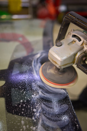 A professional technician expertly polishes glass surfaces in a workshop with precision