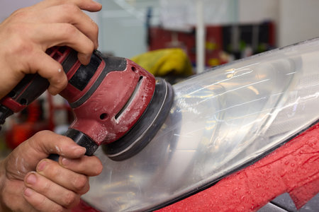 Person using a machine to polish automotive lighting on a car headlightの写真素材