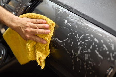 A detailed process of cleaning a car using a yellow cloth for optimal cleanliness and shine