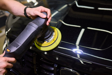 Person using machine to polish black cars automotive exterior
