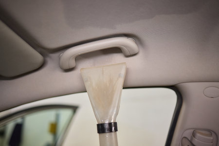 Man is using a vacuum cleaner and wearing protective goggles while cleaning the interior of a carの写真素材