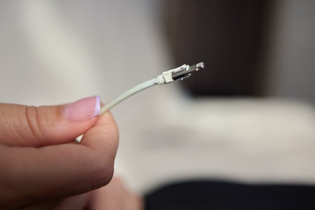 The image shows a closeup of someone gripping a lightning cable that appears to be damaged
