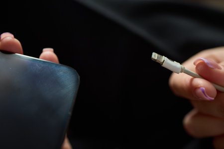 The image shows a closeup of someone gripping a lightning cable that appears to be damaged