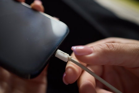 The image shows a closeup of someone gripping a lightning cable that appears to be damagedの写真素材