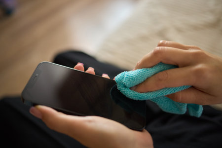 A person is using a microfiber cloth to clean their smartphone for hygiene purposesの写真素材