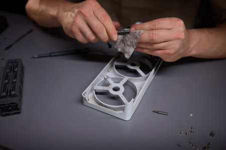 A technician is skillfully repairing a computer GPU fan with precision tools in a workshop