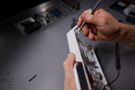 A technician is skillfully repairing a computer GPU fan with precision tools in a workshopの写真素材