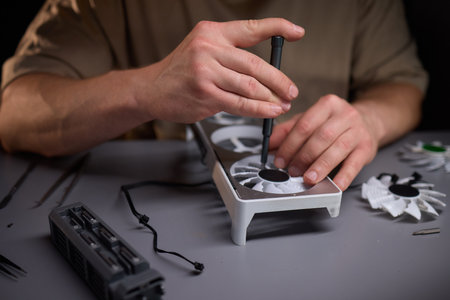 A technician is skillfully repairing a computer GPU fan with precision tools in a workshopの写真素材