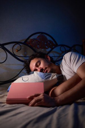 A person peacefully asleep with a book covering their face in a bedroom, enjoying a quiet nightの写真素材