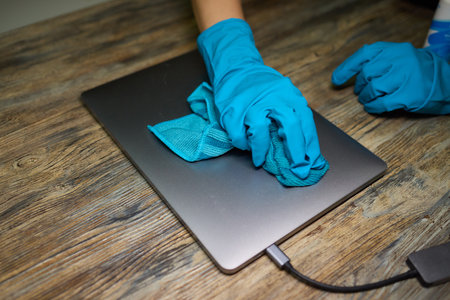 Maintaining laptop hygiene and care with gloves for cleanliness and technology preservationの写真素材