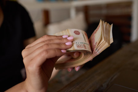 Woman with pink nails counts money, focused on cash, involved in finance and transactionsの写真素材