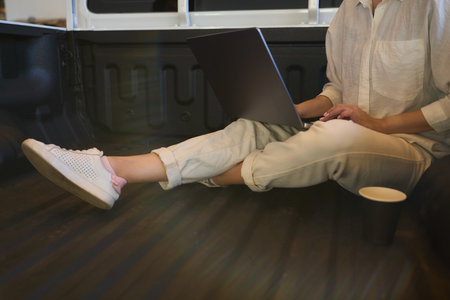 A person is working on a laptop inside a car during their commute to a destinationの写真素材