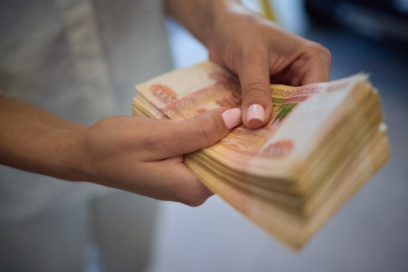 Woman with pink nails counts money, focused on cash, involved in finance and transactionsの写真素材