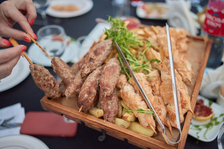 Savor tasty Meat Skewers and crispy Fries on a Wooden Platter at an Outdoor Dining Eventの写真素材