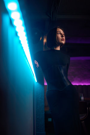 An Elegant Model Dressed in a Chic Black Outfit Poses at a Modern Bar Setting for Photographyの写真素材