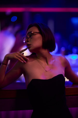 A stylish woman struts into the bar at night, exuding elegance and seduction of nightlife