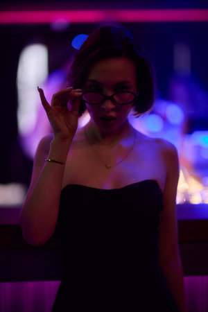 A stylish woman struts into the bar at night, exuding elegance and seduction of nightlifeの写真素材