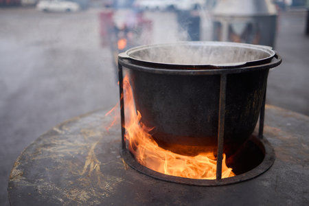 The Glow of Embers and Flames in a Steel Cooking Pot Outdoors Under the Starry Skyの写真素材