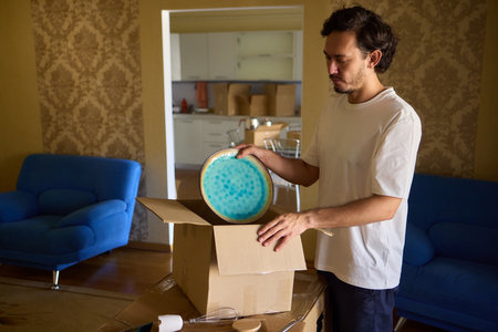 A man is unpacking boxes in his new home, organizing his belongings after relocationの写真素材