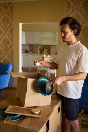 A man is unpacking boxes in his new home, organizing his belongings after relocationの写真素材