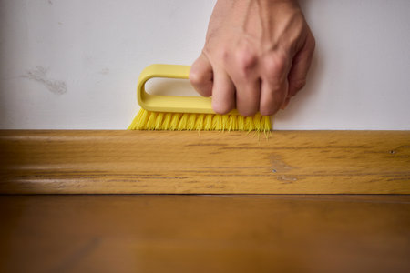 Cleaning a Wooden Floor using a Yellow Brush for Optimal Hygiene and Cleanlinessの写真素材