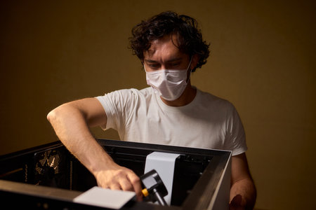 A man cleans a computer case with a vacuum in a bright room, stressing workspace tidiness