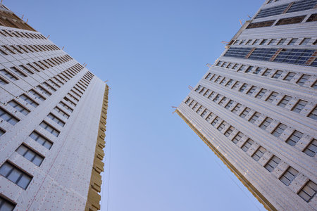 The modern architectural facade stands strikingly under a bright, clear blue sky above it
