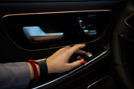 An Elegant Automobile Interior Featuring a Hand Gracefully Positioned on Door Controls