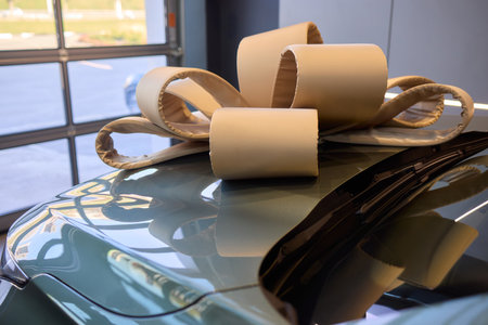 An iconic new car is being presented with a ribbon bow at the showroom for a celebratory eventの写真素材