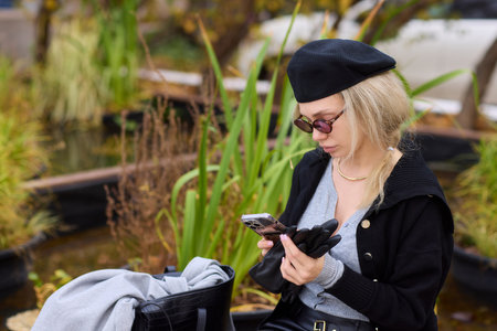 Trendy Young Woman Engaged with Her Smartphone While Surrounded by Beautiful Nature