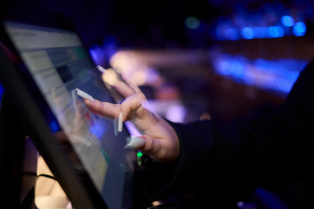 A Close Up Image of a Hand Actively Using a Touchscreen Device in a Dimly Lit Environmentの写真素材