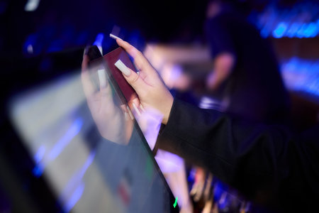 A Close Up Image of a Hand Actively Using a Touchscreen Device in a Dimly Lit Environment