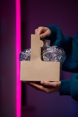 Hands holding a stylish brown paper basket that features a shiny metallic foil lid designの写真素材