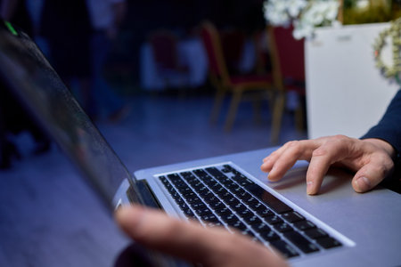 A Focused Hands Actively Typing on Laptop in a Dimly Lit Setting to Enhance Productivityの写真素材