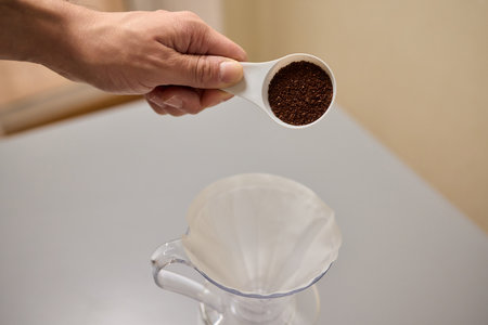 Pouring freshly ground coffee beans into a measuring cup for a perfect morning brewの写真素材