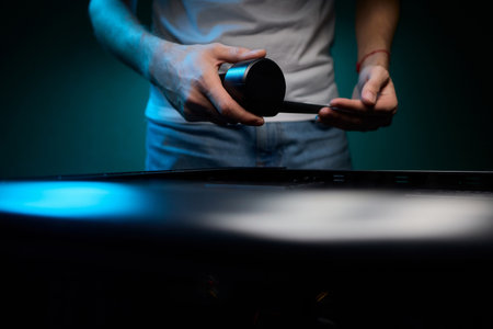 A vacuum is being used to clean a computer case in a room with blue ambient lightingの写真素材