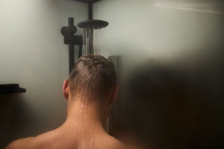 Water streams from a modern showerhead in a contemporary bathroom settingの写真素材