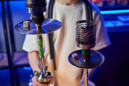 Close up of a hookah made of metal and glass on a wooden table