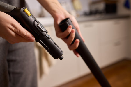 Hands actively using a vacuum cleaner in a clean and modern kitchen environment